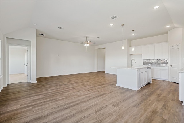 kitchen with a kitchen island with sink, ceiling fan, decorative backsplash, white cabinetry, and decorative light fixtures