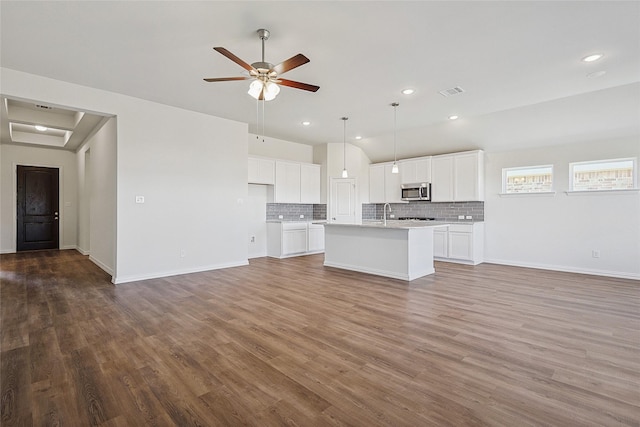 kitchen featuring an island with sink, hardwood / wood-style floors, decorative backsplash, white cabinets, and ceiling fan