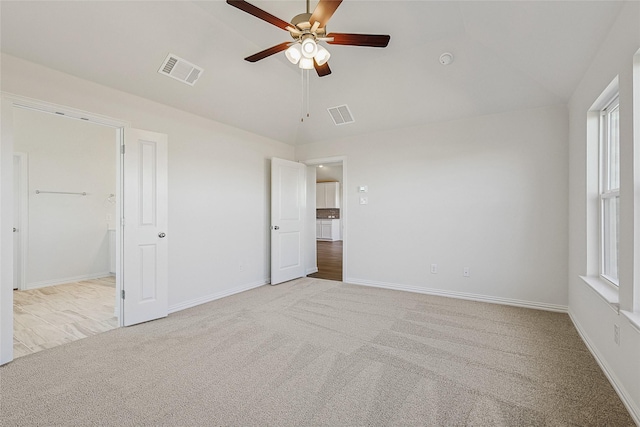 unfurnished bedroom featuring multiple windows, ceiling fan, vaulted ceiling, and light colored carpet