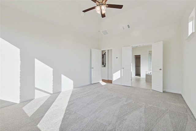 carpeted empty room featuring ceiling fan and high vaulted ceiling