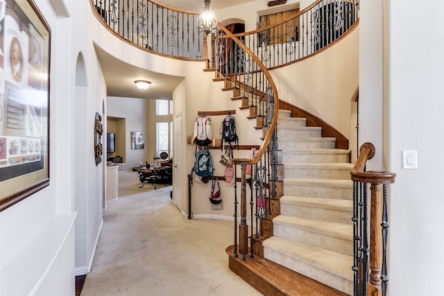 staircase featuring a towering ceiling and carpet flooring