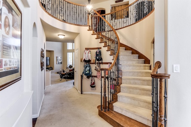staircase with a high ceiling, baseboards, arched walkways, and carpet floors