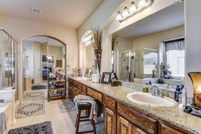 ensuite bathroom with double vanity, visible vents, a shower stall, and a sink