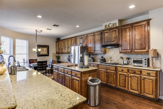 kitchen featuring sink, a center island, pendant lighting, dark wood-type flooring, and stainless steel fridge with ice dispenser