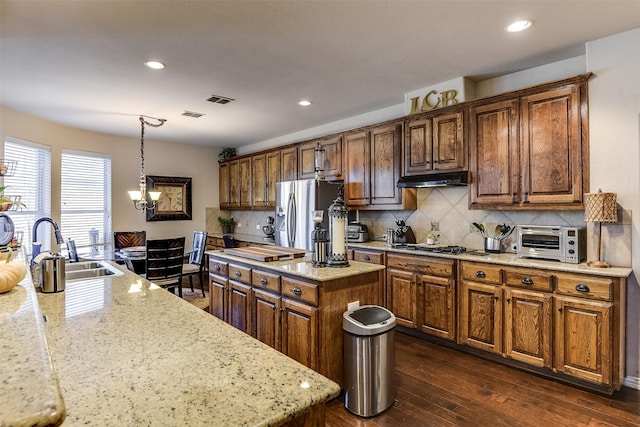 kitchen with a toaster, stainless steel appliances, under cabinet range hood, a kitchen island, and a sink