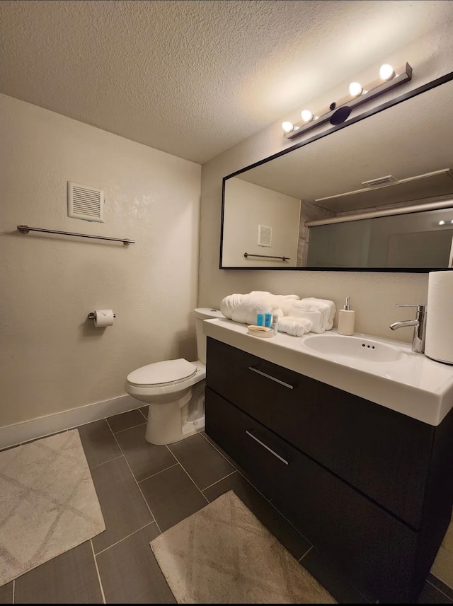 bathroom with toilet, a textured ceiling, vanity, and tile patterned floors