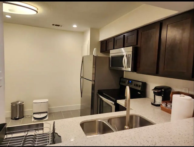 kitchen featuring dark brown cabinetry, light stone counters, electric range, and sink