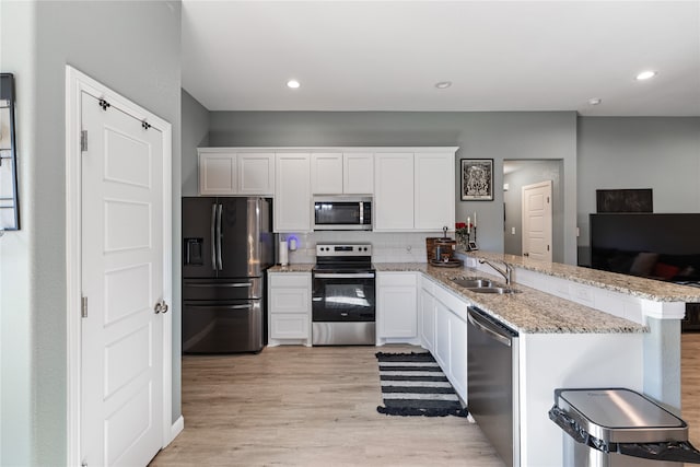 kitchen featuring sink, kitchen peninsula, light hardwood / wood-style floors, stainless steel appliances, and white cabinets