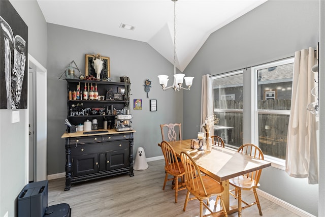 dining space featuring light hardwood / wood-style floors, a chandelier, plenty of natural light, and vaulted ceiling