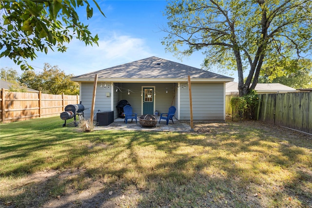 rear view of property with a yard, a patio, and an outdoor fire pit