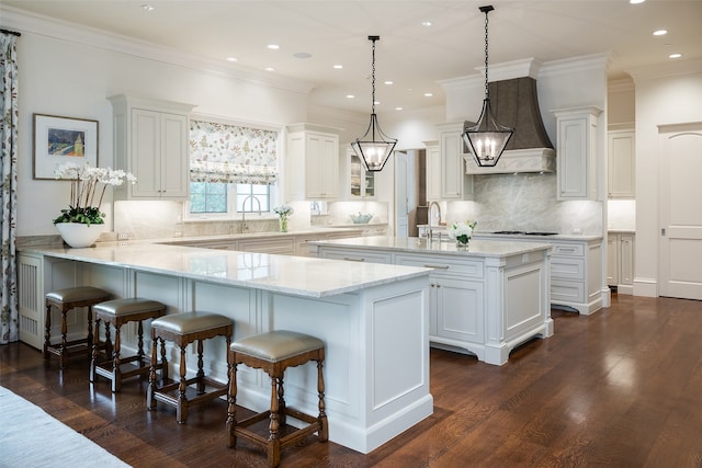 kitchen featuring a kitchen breakfast bar, white cabinetry, hanging light fixtures, and dark hardwood / wood-style flooring