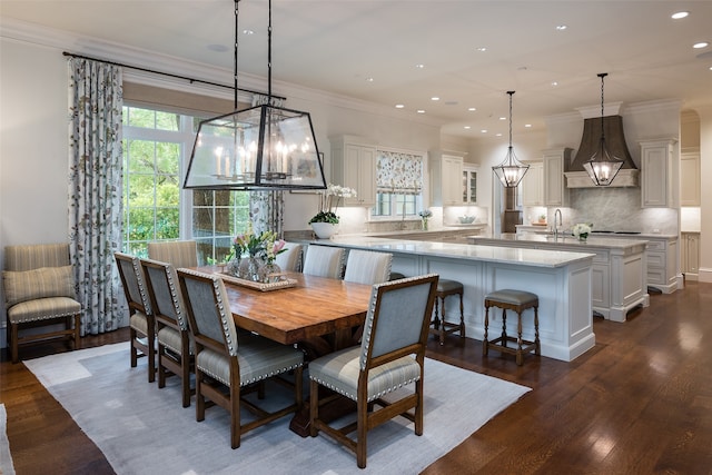 dining area with sink, a notable chandelier, ornamental molding, and dark hardwood / wood-style flooring