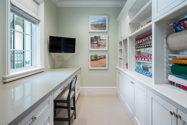 carpeted office space featuring built in desk and crown molding