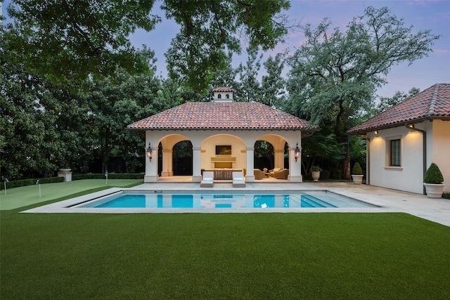 pool at dusk with a yard and a patio