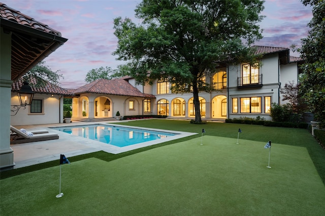 pool at dusk featuring a patio