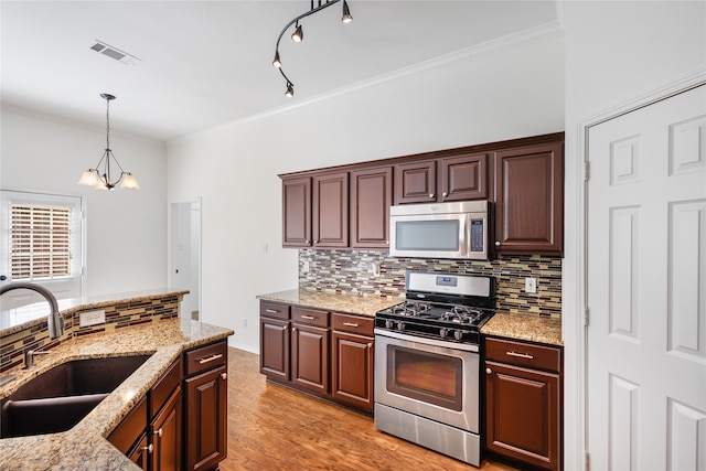 kitchen with sink, stainless steel appliances, pendant lighting, ornamental molding, and light hardwood / wood-style flooring