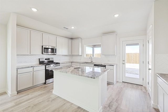 kitchen with white cabinetry, a center island, stainless steel appliances, and light stone countertops