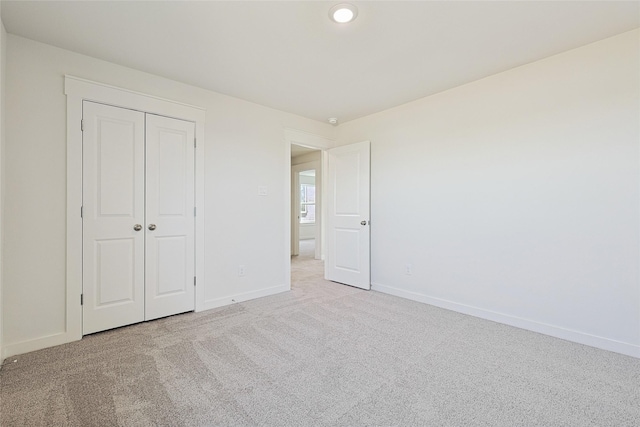 unfurnished bedroom with light colored carpet and a closet