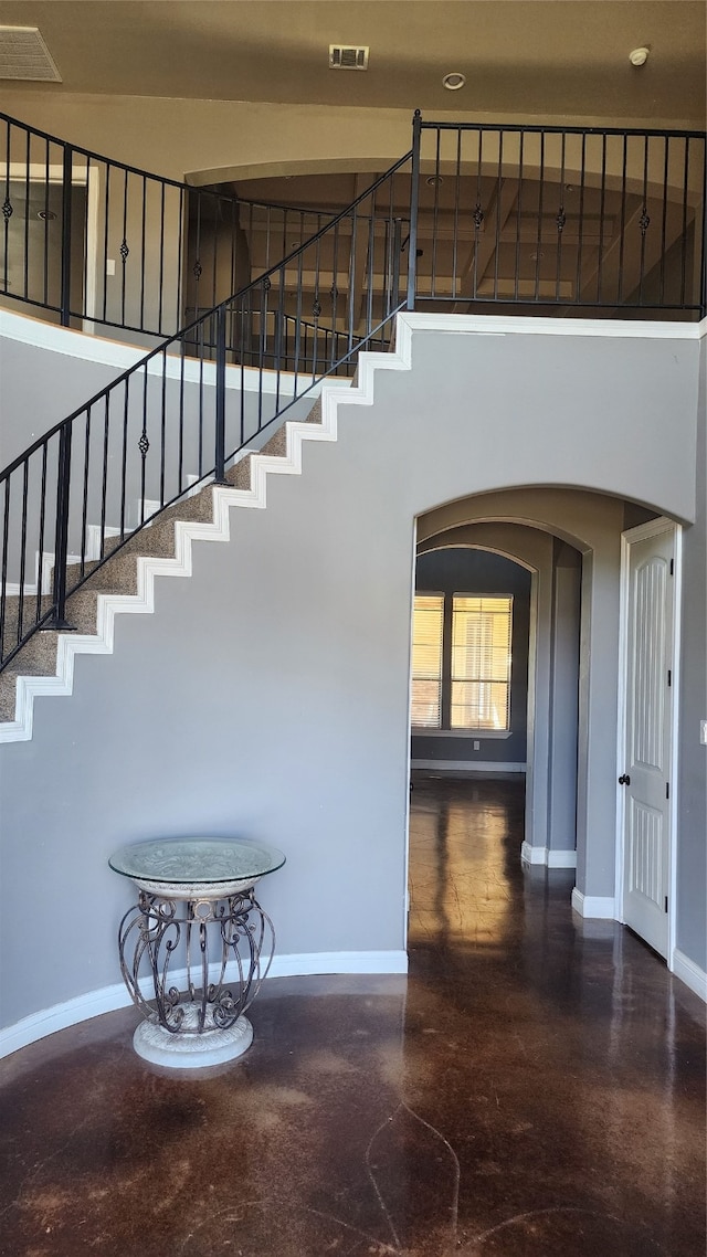 staircase with concrete floors and a high ceiling