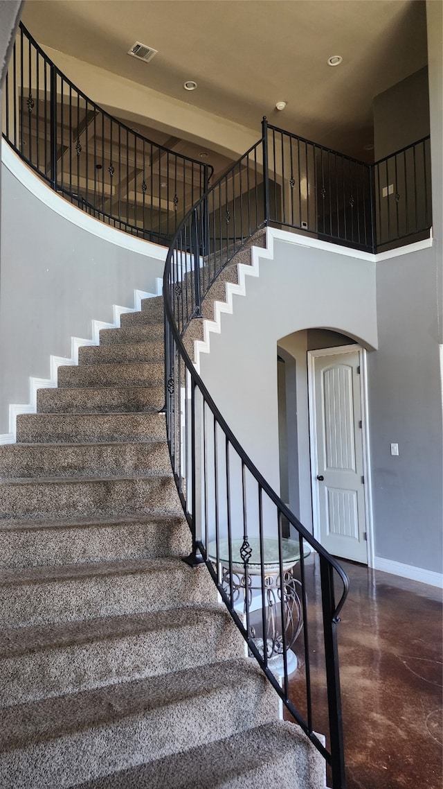 stairway featuring a towering ceiling and concrete floors