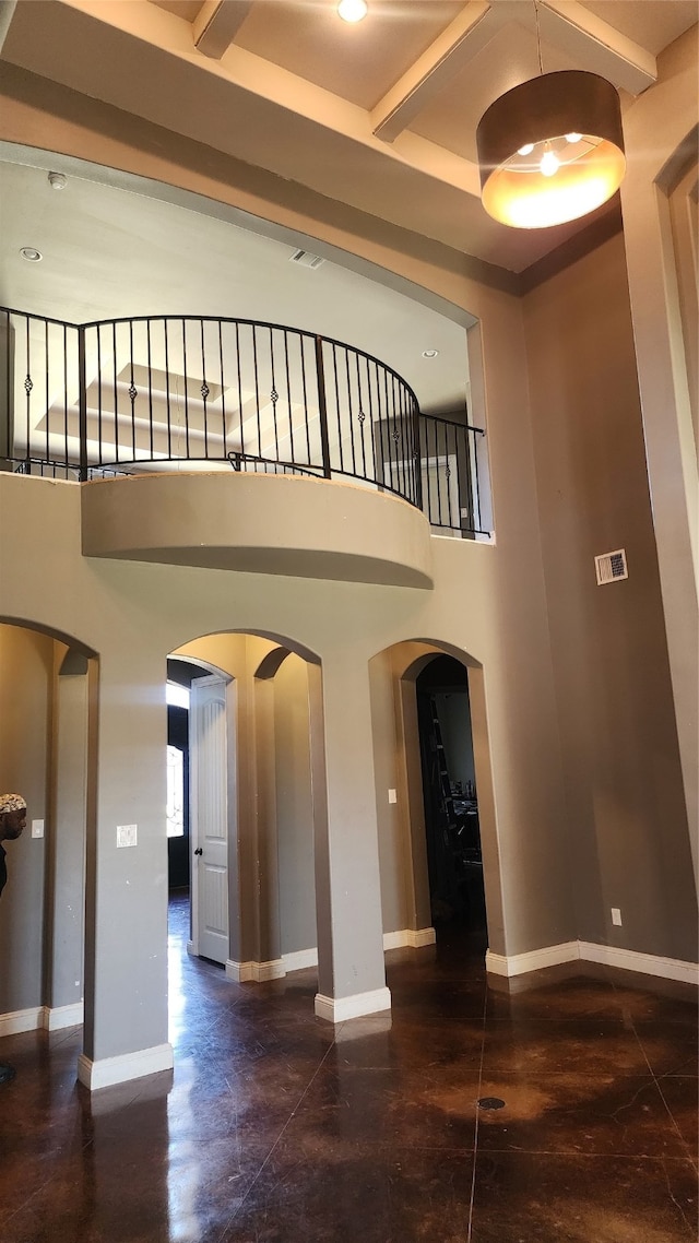 stairway with beamed ceiling and a high ceiling