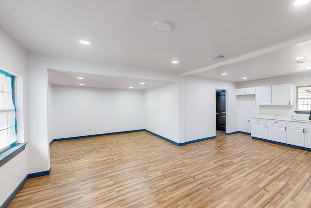 kitchen with light hardwood / wood-style floors, white cabinets, and sink