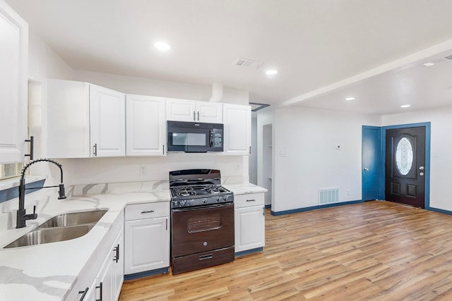 kitchen featuring sink, black appliances, white cabinetry, light stone counters, and light hardwood / wood-style floors