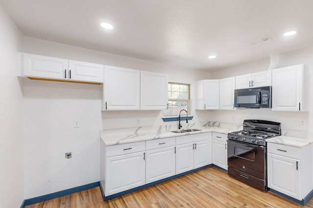 kitchen featuring sink, light stone countertops, black appliances, white cabinetry, and light hardwood / wood-style floors