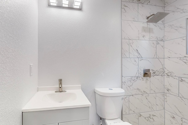 bathroom featuring a tile shower, toilet, and vanity