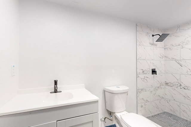 bathroom with toilet, vanity, and a tile shower