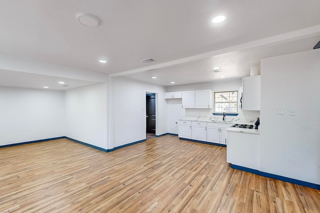 kitchen with sink, light hardwood / wood-style flooring, and white cabinets