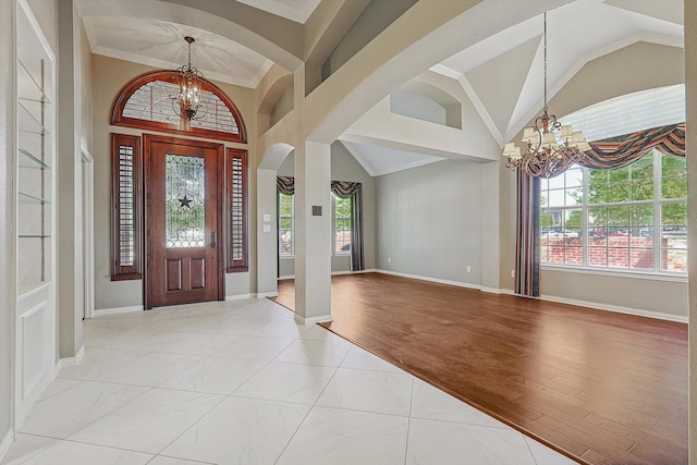 entrance foyer with a healthy amount of sunlight, crown molding, a chandelier, and light wood-type flooring