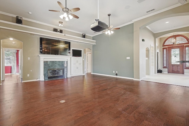 unfurnished living room featuring crown molding, wood-type flooring, a premium fireplace, and ceiling fan