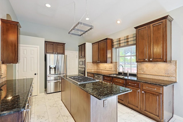 kitchen with sink, dark stone countertops, appliances with stainless steel finishes, a kitchen island, and backsplash