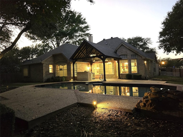 rear view of property with a fenced in pool and a patio