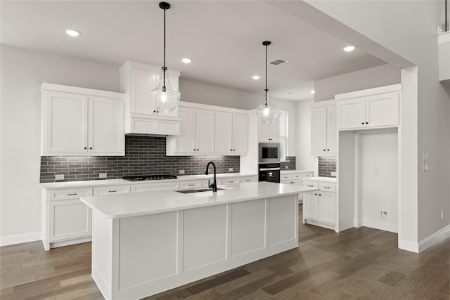 kitchen featuring visible vents, a sink, wall oven, stainless steel microwave, and black cooktop