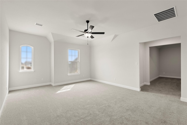 carpeted spare room with visible vents, baseboards, and a ceiling fan