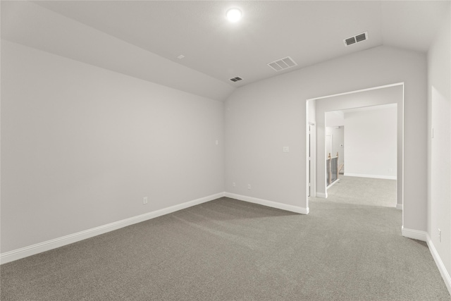 empty room with visible vents, baseboards, vaulted ceiling, and carpet floors