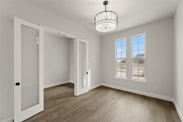 unfurnished bedroom featuring visible vents, baseboards, and wood finished floors