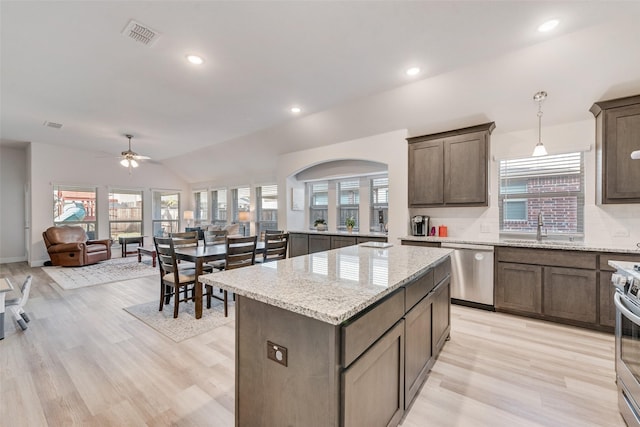 kitchen with pendant lighting, sink, appliances with stainless steel finishes, light stone counters, and a kitchen island