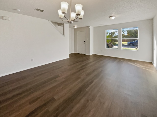 interior space with dark wood-type flooring, a textured ceiling, and a chandelier