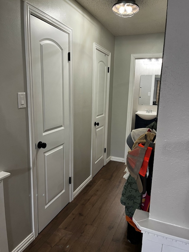 corridor with a textured ceiling and dark hardwood / wood-style floors