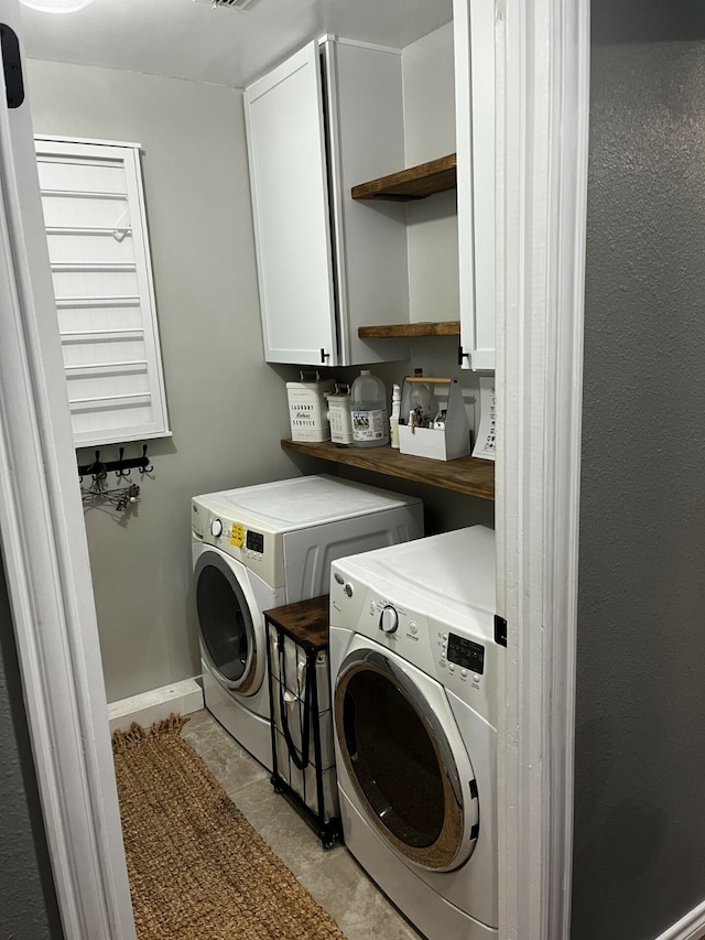 laundry area featuring cabinets, washer and clothes dryer, and light tile patterned floors