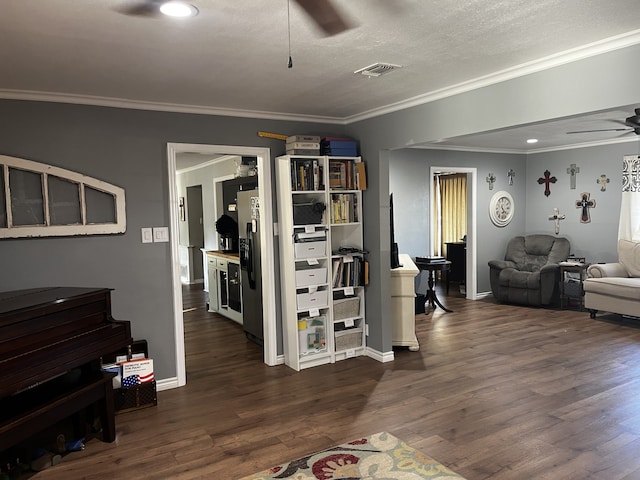 living room featuring ornamental molding, a textured ceiling, dark wood-type flooring, and ceiling fan