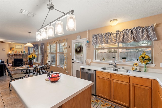 kitchen featuring sink, pendant lighting, a center island, dishwasher, and a stone fireplace