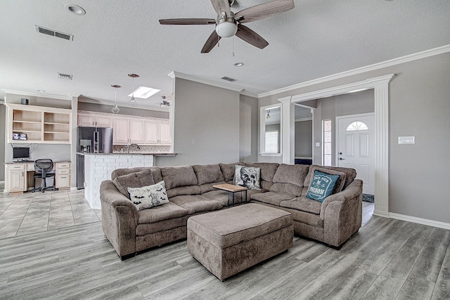 living room with ceiling fan, crown molding, a textured ceiling, and light hardwood / wood-style flooring