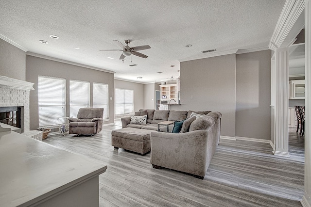 living room featuring light hardwood / wood-style floors, crown molding, a textured ceiling, and a fireplace