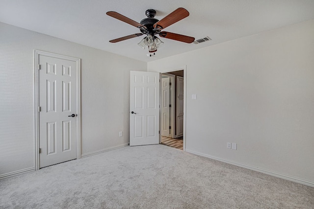 unfurnished bedroom with a closet, light colored carpet, and ceiling fan