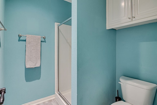 bathroom with a shower with door and toilet