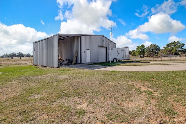 view of outdoor structure with a garage, a lawn, and a rural view